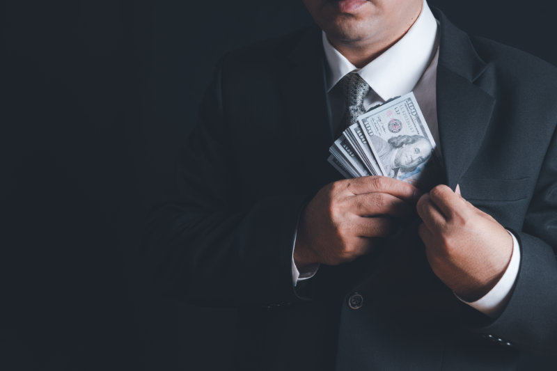 Man putting bribe money into pocket on black background, Concept for corruption, finance profit, bail and crime